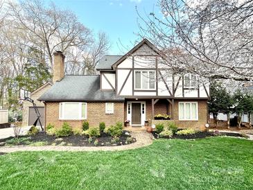 Charming Tudor-style home featuring a brick facade, dark trim, manicured lawn, and beautiful landscaping at 5217 Camilla Dr, Charlotte, NC 28226