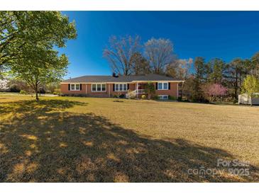 Charming single-story brick home with a well-manicured lawn and mature trees on a sunny day at 1139 Suttle Rd, Lancaster, SC 29720