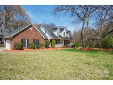 Charming two-story brick home boasts a well-manicured lawn, black shutters, and a welcoming front porch at 4436 Roberta Rd, Concord, NC 28027