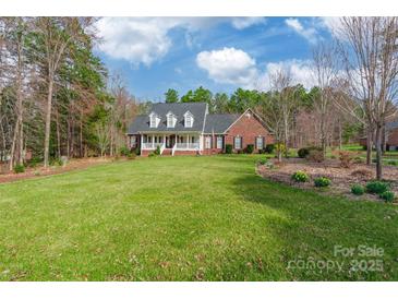 Charming brick home featuring a well-manicured lawn, lush trees, and a welcoming front porch at 514 Saint Johns Dr, Salisbury, NC 28144