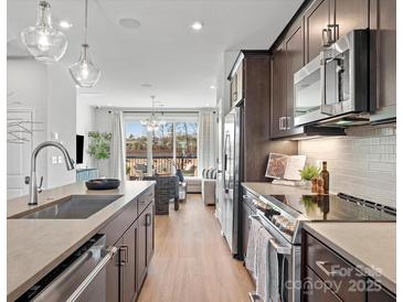 Modern kitchen featuring stainless steel appliances, center island, and open layout to the living area at 5719 Castlerea Dr, Charlotte, NC 28217