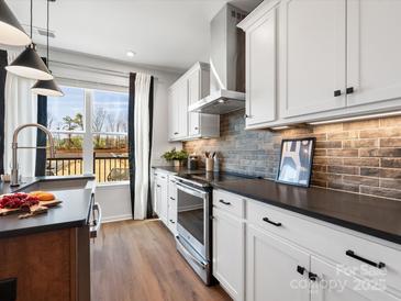 Modern kitchen featuring stainless steel appliances, granite counters, and a beautiful brick backsplash at 5731 Castlerea Dr, Charlotte, NC 28217