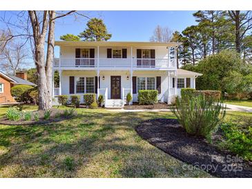 Charming two-story white brick home featuring a double front porch and well-maintained landscaping at 5943 Charing Pl, Charlotte, NC 28211