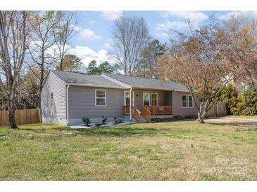 Charming single-story home with a well-maintained yard, inviting front porch, and mature trees at 9105 Touchstone Ln, Charlotte, NC 28227