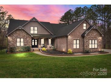 Charming brick and stone home with a well-manicured lawn and inviting front porch, blending elegance with comfort at 1770 Cranwell Dr, Mt Ulla, NC 28125
