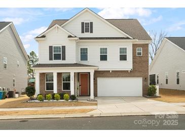 Inviting two-story home featuring brick and white siding, a well-manicured lawn, and an attached two-car garage at 3008 Quinebaug Rd, Fort Mill, SC 29715