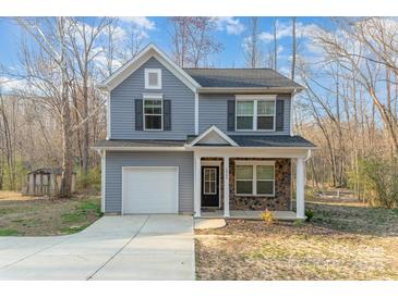 Charming two-story home with gray siding, stone accents, a covered porch, and an attached garage at 3944 Wade E Morgan Rd, Charlotte, NC 28269