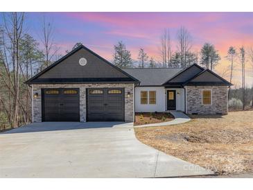A charming single-story home with a stone and gray shingle accent and a two car garage at 24 Eastwinds Dr, Hickory, NC 28601