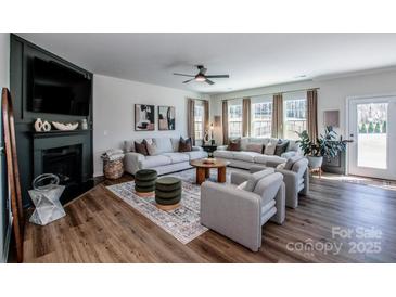 Spacious living room featuring two sofas, a ceiling fan, and a fireplace with decorative elements at 242 Hamptons Cove Rd, Troutman, NC 28166