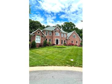 Charming red brick two-story home with a well-manicured green lawn and lush trees at 8011 Greencastle Dr, Charlotte, NC 28210