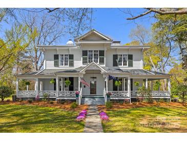 Charming two-story home with a large wrap-around porch, manicured lawn, and mature trees, perfect for outdoor living at 121 N Congress St, York, SC 29745