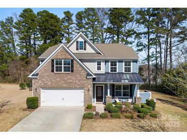 Beautiful two-story home features a manicured lawn, brick accents, and a cozy front porch sitting area at 15916 Foreleigh Rd, Huntersville, NC 28078