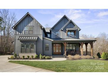 Stunning two-story home features a covered porch with timber columns and a beautifully landscaped front yard at 180 Twin Sisters Ln, Mooresville, NC 28117