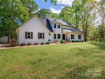 Charming white brick home with brown shutters and lush green lawn, surrounded by mature trees at 207 Windsor Greene Dr, Monroe, NC 28110