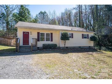 Charming single-story home featuring yellow siding, a red front door, and well-maintained landscaping at 570 N Rhyne St, Gastonia, NC 28054