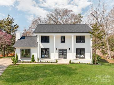 Stunning white brick two-story home with large pillars, black trim, covered entry, and expansive front lawn at 7801 Snowden Ln, Charlotte, NC 28270