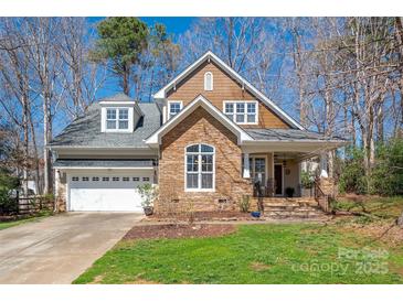 Charming home showcasing a stone and shingle facade, complemented by a manicured lawn and attached two-car garage at 7806 Spanish Oaks Dr, Waxhaw, NC 28173