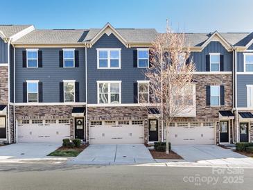 Charming townhome featuring stone accents, gray siding, black shutters, and two-car garage at 1814 Shumard Ln, Charlotte, NC 28205