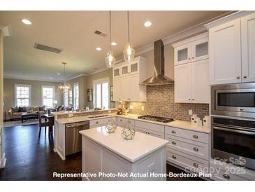 Bright kitchen boasts white cabinets, stainless steel appliances, pendant lighting and center island at 19724-A School St, Cornelius, NC 28031