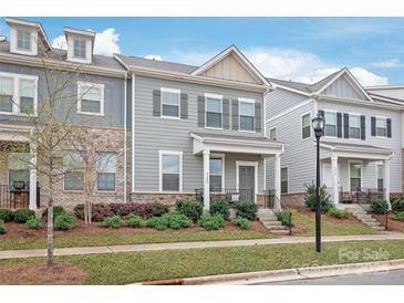 Charming townhome with grey siding, a covered front porch, and lush landscaping at 4102 Harmony Hills Dr, Matthews, NC 28104