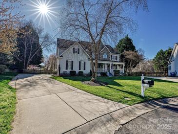 Charming two-story home with a well-manicured front yard and a long driveway on a sunny day at 20313 Queensdale Dr, Cornelius, NC 28031