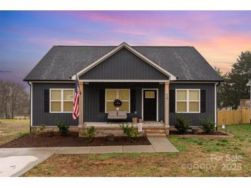 Charming single-story home featuring a cozy front porch, American flag, and tidy landscaping at 619 N Skyland Dr, Mount Pleasant, NC 28124