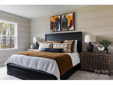 Modern bedroom featuring a black bed frame, textured bedding, and stylish bedside table with decor at 3012 Hutton Gardens Ln, Charlotte, NC 28269