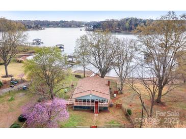 Aerial view of charming blue house by the lake surrounded by lush greenery and mature trees at 119 Hogan Ln, Mooresville, NC 28117