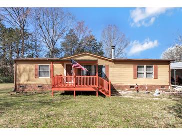 Charming tan home with a red porch, American flag, and mature trees on a sunny day at 3080 Sims Rd, Rock Hill, SC 29730