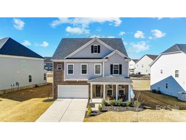 Charming two-story home featuring gray siding, brick accents, a two-car garage, and a welcoming front porch at 4208 Stream Dale Nw Cir, Concord, NC 28027