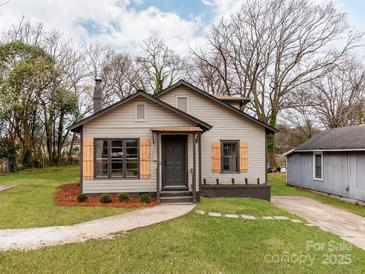 Charming home featuring a quaint front yard, fresh landscaping, and light gray siding with dark gray trim at 507 N Oakland St, Gastonia, NC 28052