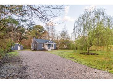 Charming blue cottage with a gravel driveway and a lush green yard at 6282 Richburg Rd, Great Falls, SC 29055