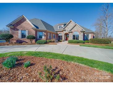 Beautiful brick home featuring stone accents, mature landscaping and a long, curved driveway at 810 Lake Wright Rd, China Grove, NC 28023