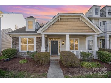 Charming home featuring stone accents, a covered porch, and manicured landscaping at dusk at 4108 Twenty Grand Dr, Indian Trail, NC 28079