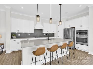 Bright kitchen features a large island with seating, stainless steel appliances, and modern pendant lighting at 11327 James Coy Rd, Davidson, NC 28036