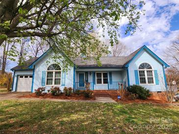 Charming blue single-story home featuring manicured front yard, flowerbeds and inviting front porch at 121 Deertrack Dr, Mount Holly, NC 28120