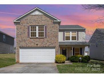 Charming two-story home featuring a brick facade, attached garage, and well-manicured lawn at 504 Zander Woods Ct, Mount Holly, NC 28120