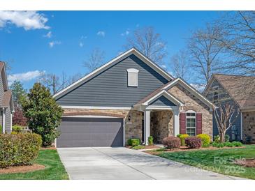 Charming home features a gray facade, stone accents, and a well-manicured lawn at 1128 Avalon Pl, Matthews, NC 28104