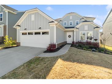 Charming, light blue home featuring an attached two-car garage, landscaped yard, and welcoming front entrance at 14235 Canemeadow Dr # 102, Charlotte, NC 28278