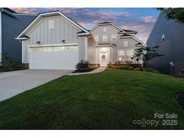 Charming two-story home boasts a manicured lawn, attached garage, and welcoming front porch under an colorful evening sky at 14235 Canemeadow Dr, Charlotte, NC 28278