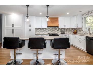 Bright kitchen with white cabinets, modern appliances, stone countertops, and stylish backsplash at 7417 Shadowlake Dr, Charlotte, NC 28226