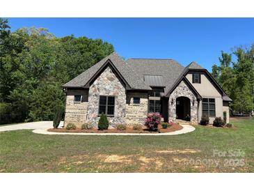 Beautiful exterior of home with stone accents, brown trim, lovely landscaping, and a manicured lawn at 1021 Mccollum Oaks Ln, Monroe, NC 28110