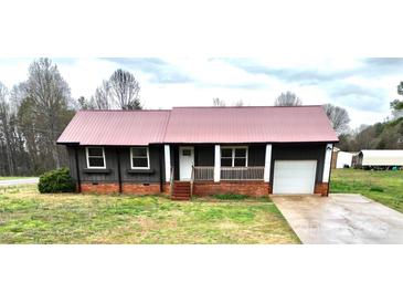 Charming single story home featuring dark siding, metal roof, a cozy front porch, and attached garage at 2180 Grace Church Rd, Salisbury, NC 28147