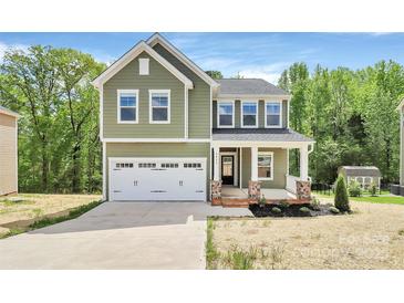 Charming two-story home with a two-car garage, inviting front porch, and manicured lawn at 2822 Woodlands Creek Dr, Monroe, NC 28110