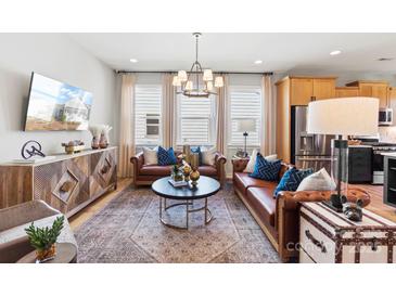 This is a living room area with two couches, hardwood floors, a coffee table, and a modern sideboard with television at 411 Sunharvest Ln, Indian Trail, NC 28079