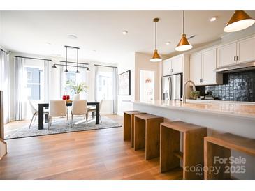 Bright dining area featuring a modern table and chairs, light hardwood floors, and large windows at 8034 Cedarsmith Ct, Charlotte, NC 28217