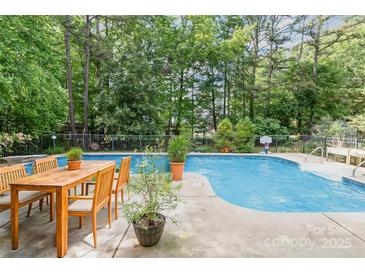 Relaxing pool area with a dining table and lush greenery creating a private oasis, perfect for outdoor entertaining at 8704 Dartmoor Pl, Mint Hill, NC 28227