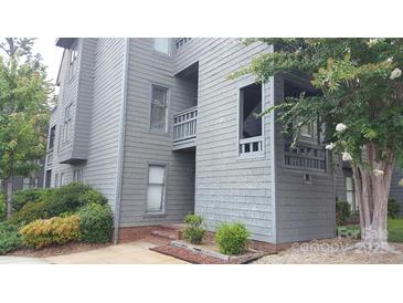 Charming condo exterior with gray siding, mature trees, and tidy landscaping, creating curb appeal at 9035 Jm Keynes Dr # 39, Charlotte, NC 28262