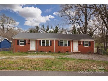 Charming brick duplex featuring black shutters, a well-maintained lawn, and convenient parking at 326 Mountain View St, Gastonia, NC 28052