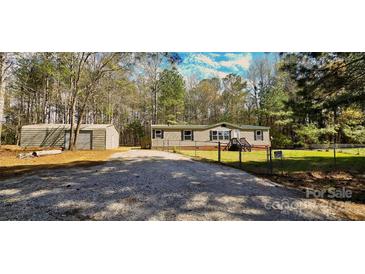 Charming single story home with a gravel driveway, fenced yard and a storage shed, surrounded by mature trees at 816 Osteen Rd, York, SC 29745